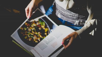 person with recipe book on their lap looking at recipe
