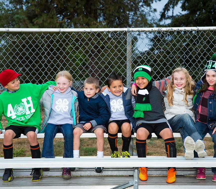 group of 4-H members sitting on athletic field bench